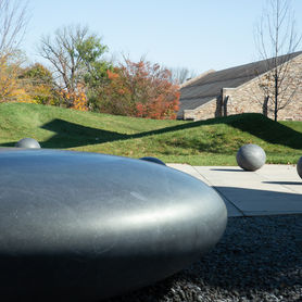 A large ovoid stone sculpture in the foreground of an outdoor space