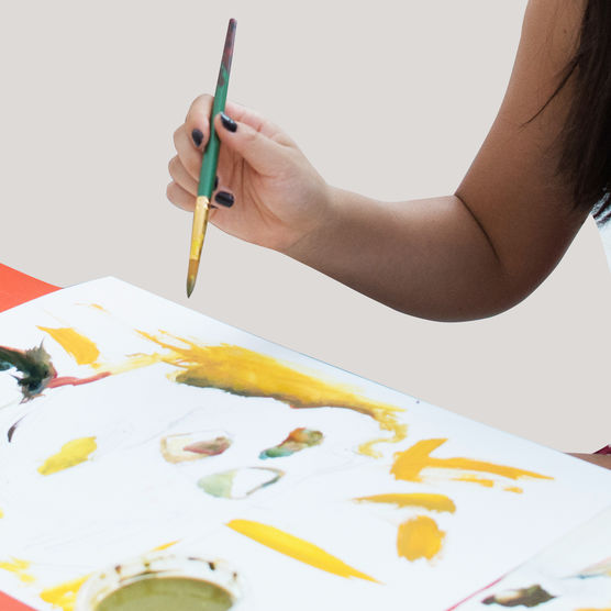 Hand of artist holding paint brush over painting.