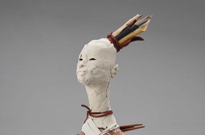 An abstracted figure with a white head wearing a crown, the body has two small loops for arms.